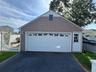 2 Car garage with a panel garage door featuring upper window lites, wood-finish siding, and a side entry door with window panes
