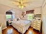 Hardwood flooring, ceiling fan with integrated lighting, window with arched architectural detail, multiple windows, built-in wall air conditioning uni
