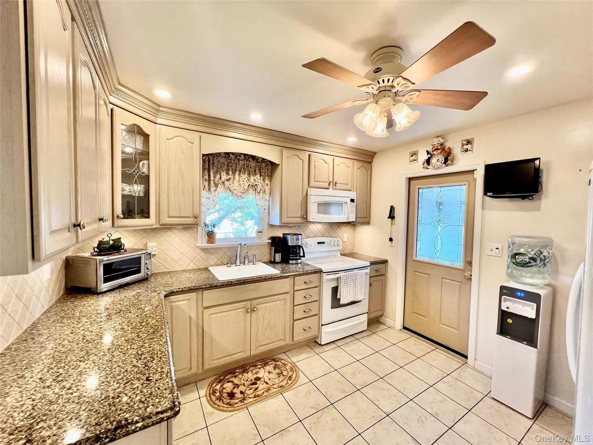 Recessed lighting, wood-finish cabinetry, granite-style countertops, tile backsplash, and tile flooring