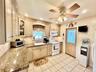 Recessed lighting, wood-finish cabinetry, granite-style countertops, tile backsplash, and tile flooring