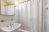 Full bathroom with a sink, shower / bathtub combination with curtain, and tile walls