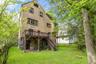 Back of house with a deck, stairs, and stone siding