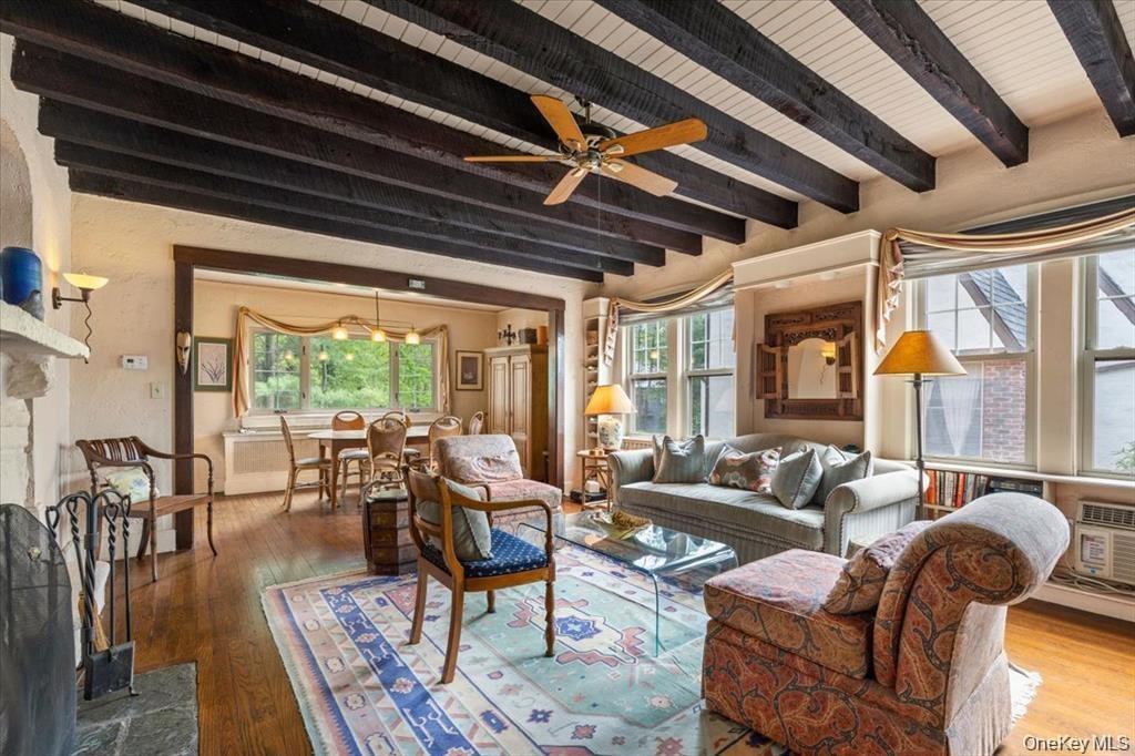Living room with beam ceiling, healthy amount of natural light, wood-type flooring, and ceiling fan