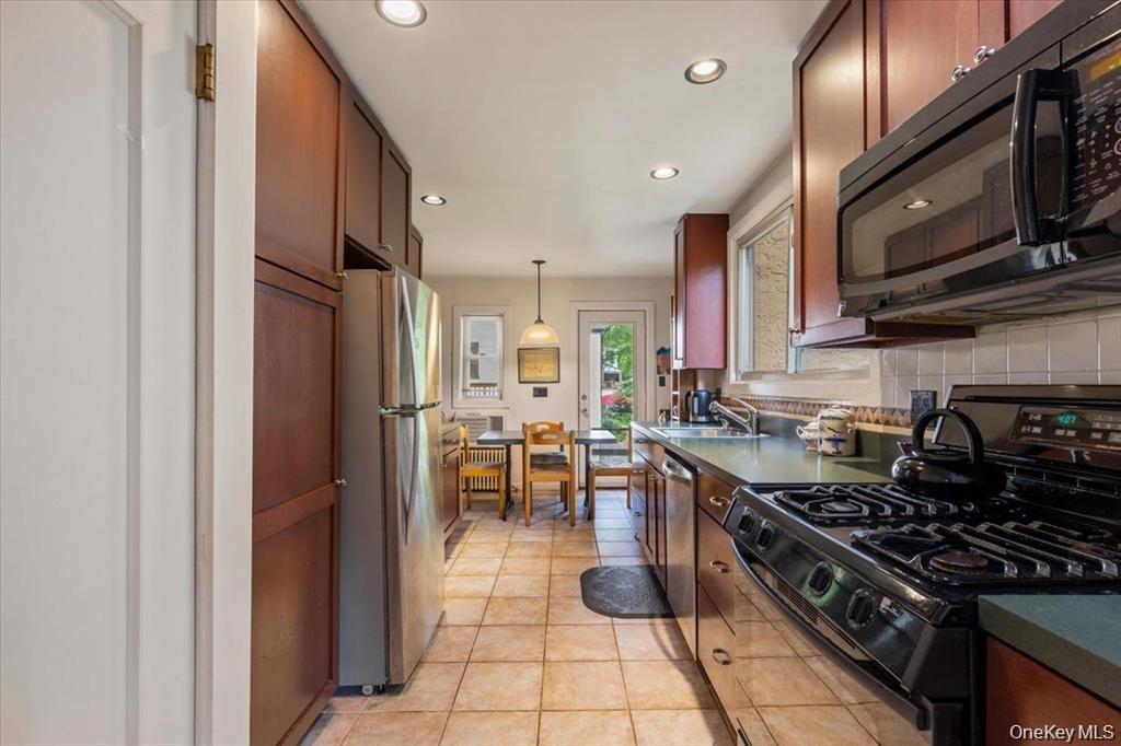 Kitchen with black appliances, dark countertops, tasteful backsplash, hanging light fixtures, and recessed lighting