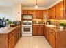 Hardwood cabinetry, stone-finish countertops, tile flooring, and integrated white appliances