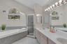 Primary bathroom featuring a built-in tub, separate shower enclosure, and a double vanity with two sinks.