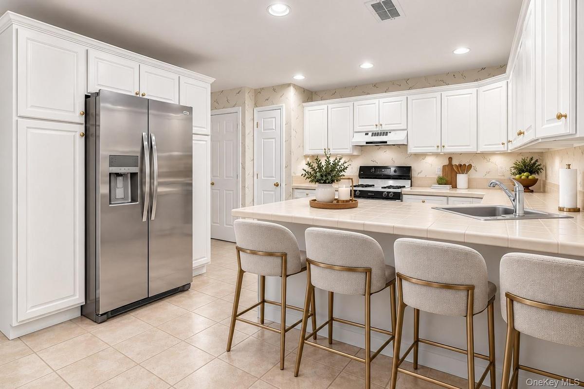 Virtually Staged.U-shaped kitchen featuring white cabinetry, light-toned countertops, and a black range.