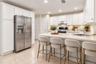 Virtually Staged.U-shaped kitchen featuring white cabinetry, light-toned countertops, and a black range.