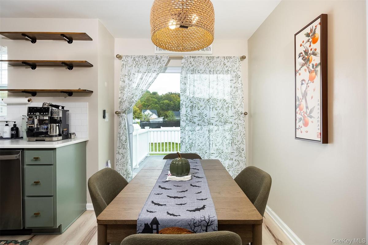 Vinyl plank flooring, light green cabinetry, white subway tile backsplash, white countertops, and a full-light patio door