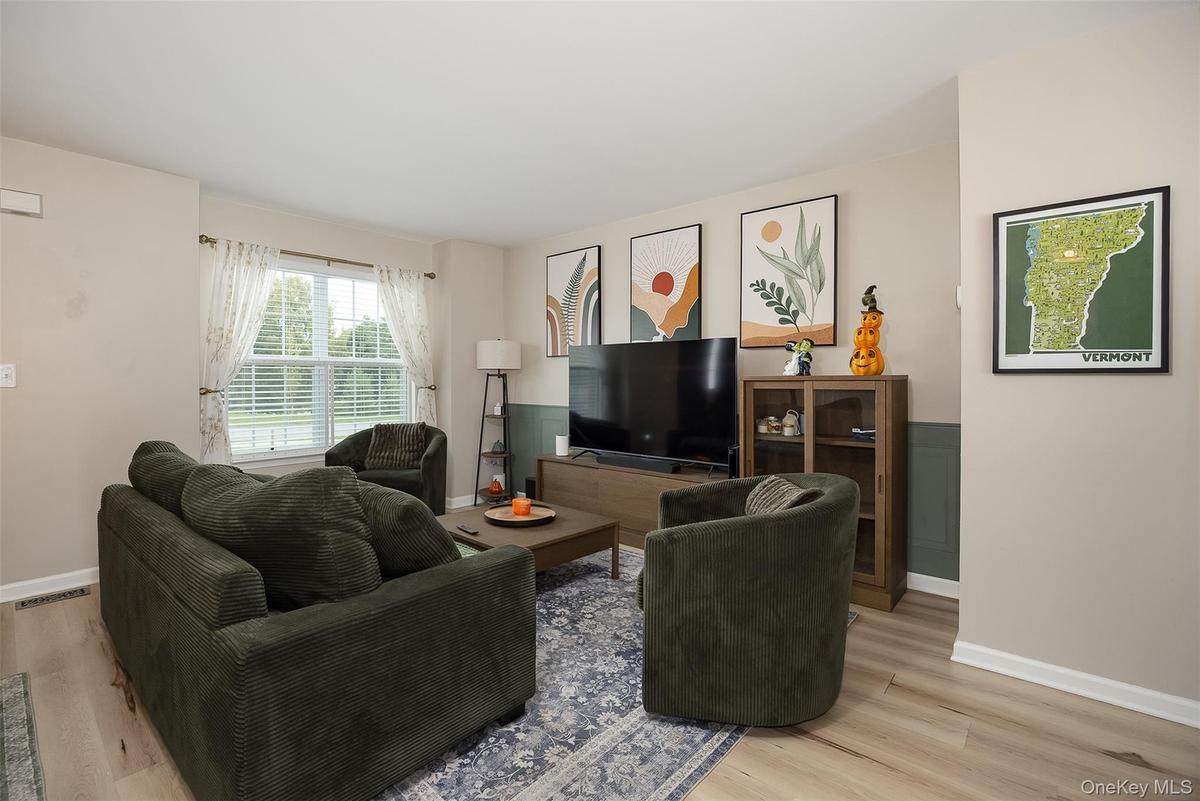 Light vinyl plank flooring, two-tone wall treatment, and a large window with blinds