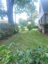 Expansive green lawn with mature trees and established hedges