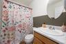 Bathroom featuring a wood-finish vanity with an integrated white sink, chrome faucet, and an oval wall-mounted mirror
