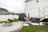 Paver patio with a stone fire pit, string lights, and a white privacy fence