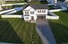 White two-story colonial-style residence with a dark shingle roof, attached two-car garage, extensive manicured lawn, and white privacy fencing