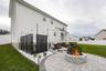 Backyard patio featuring a stone-finish fire pit, paver hardscaping, and a white privacy fence
