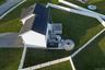 White exterior with a dark shingle roof, solar panel array, and a composite deck