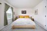 Expansive room with neutral carpeting, white walls, and a large window with blinds