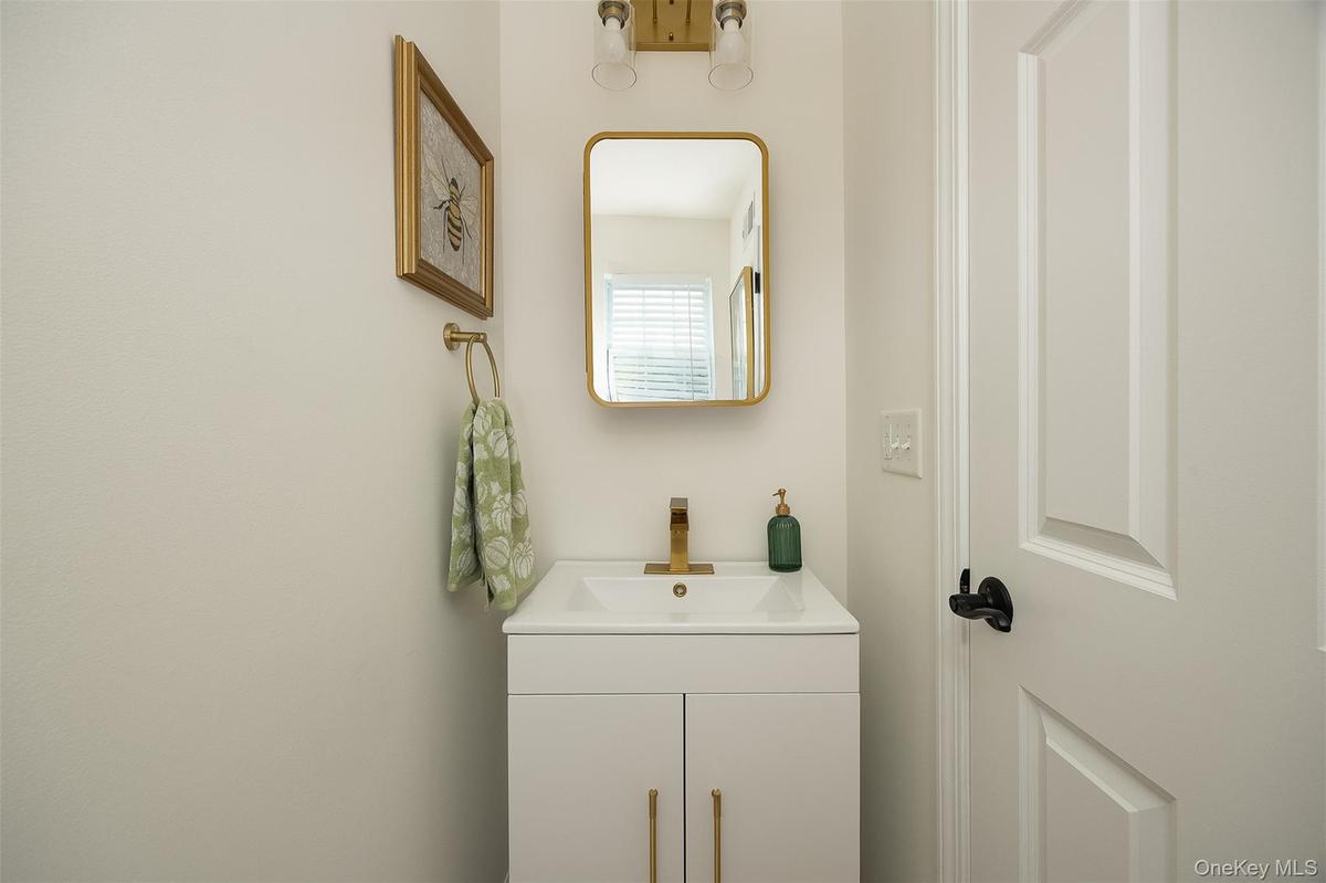 White vanity with gold-tone hardware, gold-tone faucet, and rectangular undermount sink in first floor bath