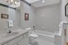 Full bathroom featuring a single vanity with an integrated sink, a large mirror, a chrome multi-bulb fixture, a toilet, and a shower and tub combined 