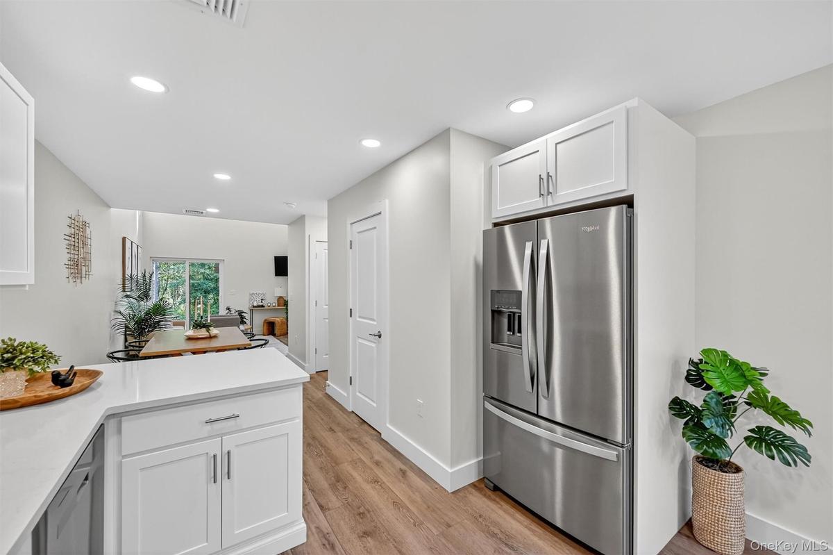 Kitchen featuring light countertops, stainless steel fridge, white cabinets, recessed lighting, and light wood-style flooring