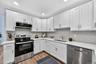 Kitchen featuring stainless steel appliances, white cabinets, light wood-style floors, tasteful backsplash, and recessed lighting