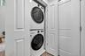 Laundry area featuring stacked washer / dryer and wood finished floors