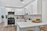 Kitchen with stainless steel appliances, white cabinets, backsplash, a breakfast bar, and recessed lighting