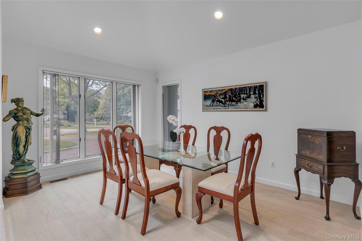 Bright dining area featuring a three-panel window, recessed ceiling lighting, and wood floors.