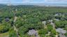 Aerial perspective showcasing a verdant, tree-lined residential area with multiple properties. Aerial Views of the proximity to the Long Island Sound.