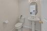 Pedestal sink with brushed nickel faucet, oval mirror, and three-light vanity fixture.