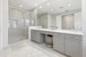 Spacious bathroom featuring a frameless glass shower enclosure, a full-width vanity mirror, light-toned tile flooring, recessed lighting, and gray sha