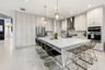 Gourmet kitchen featuring a substantial island with countertop, stainless steel appliances, extensive cabinetry, tile flooring, and integrated pendant