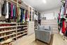 Custom closet system with extensive shelving, multiple hanging rods, built-in drawer storage, and glass-front cabinetry