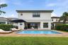 Expansive backyard featuring a clear blue swimming pool, paver deck, and manicured lawn