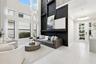 Two-story living area with expansive windows, a sleek black accent wall, and a contemporary chandelier
