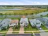 Two-story residence with a gray tile roof, light-toned exterior, paved driveway, and established landscaping