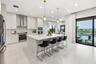 Modern kitchen featuring light-toned cabinetry, stainless steel appliances, a large center island with seating, and tile flooring