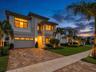 Contemporary architectural style featuring large windows, a paver driveway, manicured landscaping, and exterior architectural lighting