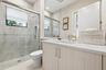 Walk-in shower with glass enclosure, integrated shower niche, and large format wall tiling