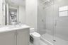 Contemporary bathroom featuring a single vanity with light grey cabinetry, a rectangular undermount sink, and a glass-enclosed shower with a chrome sh