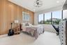 Wood-slat accent wall, large picture windows, recessed lighting, ceiling fan, and light-toned carpeting