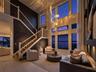 Two-story living area with high ceilings, multi-pane windows, and a built-in staircase featuring white balusters and wood treads