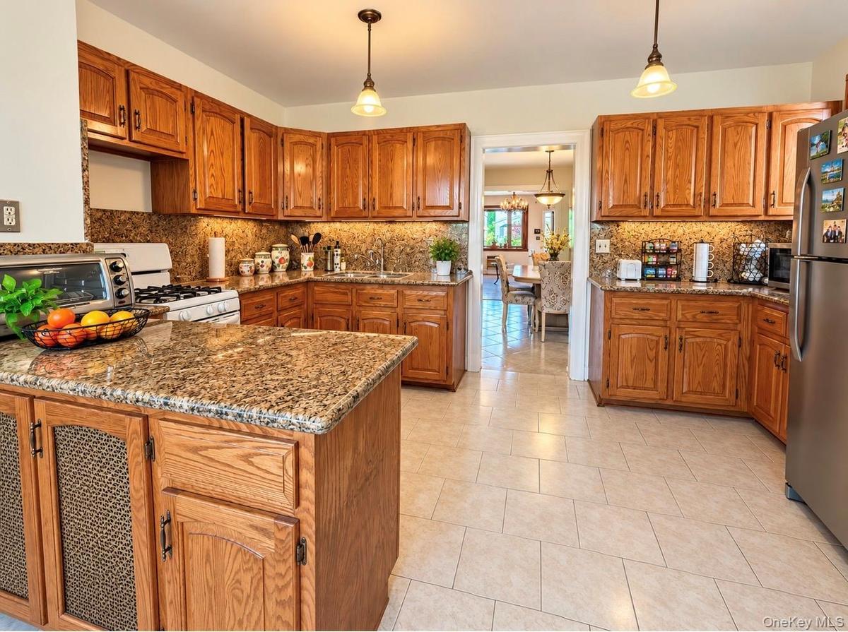 Kitchen featuring wood cabinetry, granite countertops, tile flooring, and pendant lighting