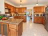 Kitchen featuring wood cabinetry, granite countertops, tile flooring, and pendant lighting