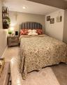 Recessed lighting, tiled flooring, upholstered headboard, and wood-finish nightstands