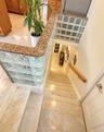 Staircase featuring light-toned tiled steps and a wood handrail