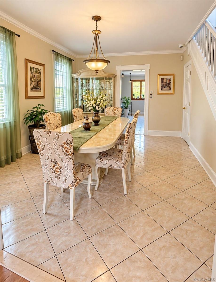 Tile flooring with contrasting border, crown molding, and a chandelier lighting fixture