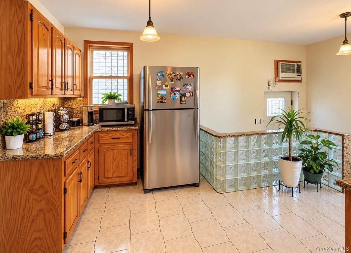 Wood-finish cabinetry, stone countertops, tile flooring, and a glass block architectural feature