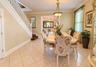 Tiled flooring, white painted staircase, recessed wall mirror, and a classic chandelier