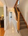 Tiled flooring, staircase with carpeted treads, wood-finish handrail, and white balusters